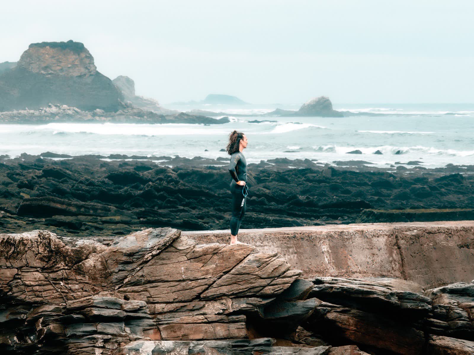 Florian standing on the rocks of a wild coastline, facing the sea