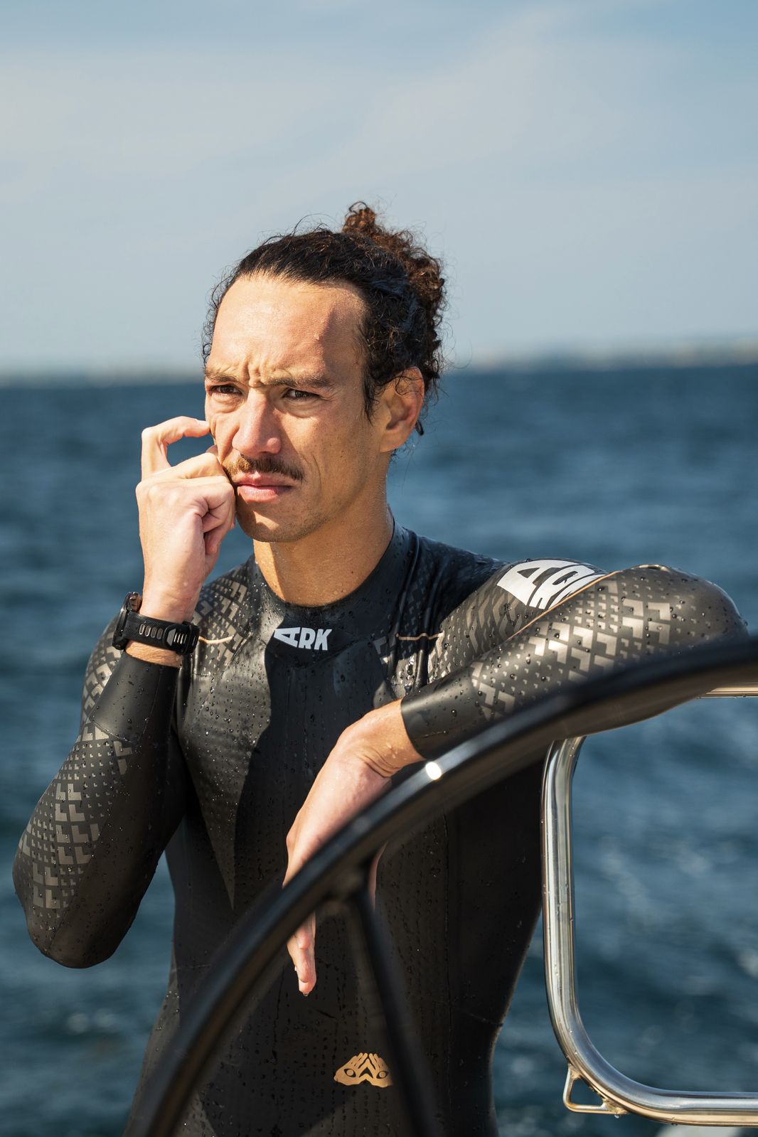 Florian in his wetsuit, hand on his chin, thinking it over