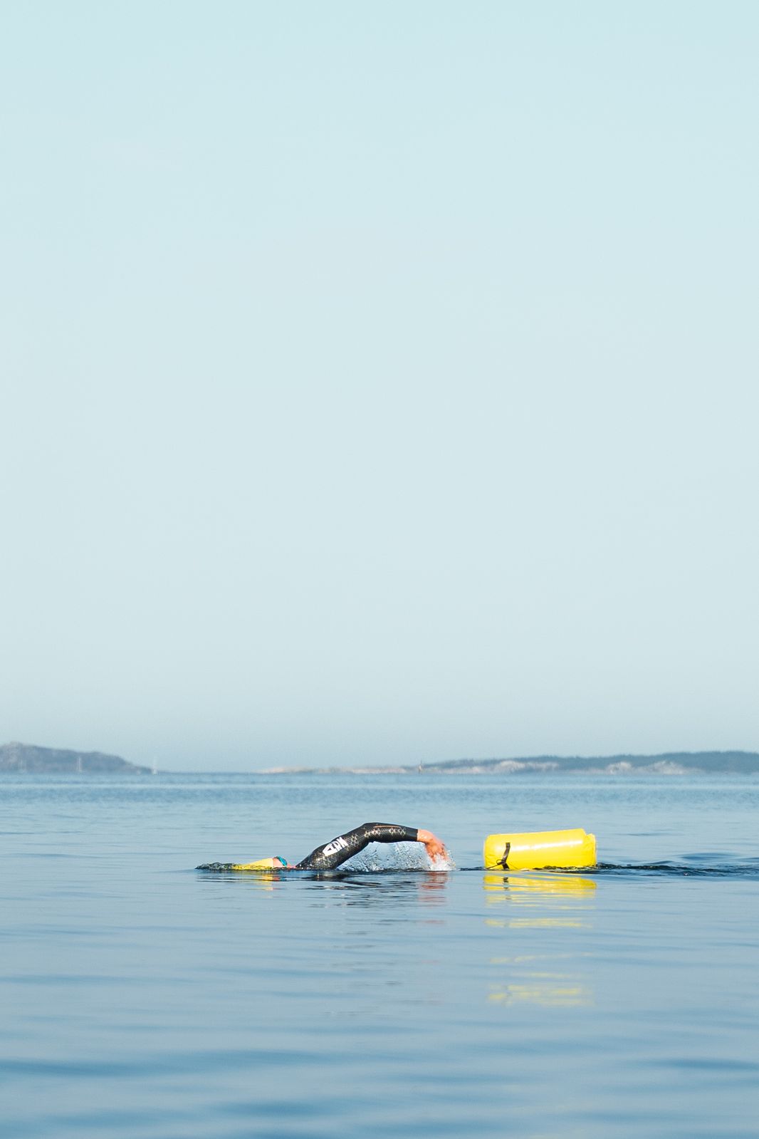 Florian swimming in a calm open sea, a yellow buoy beside him