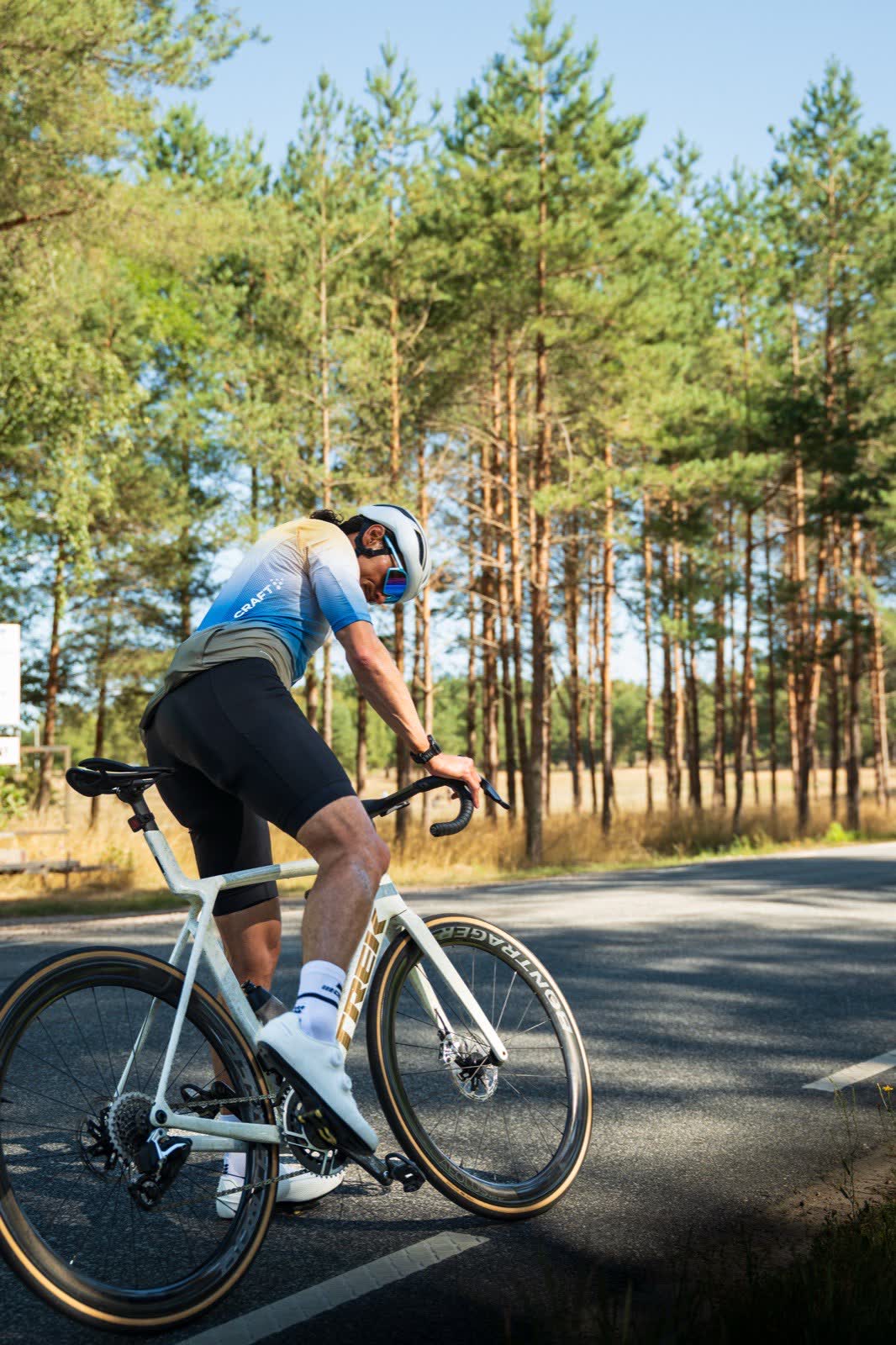 Florian riding a road bike along a pine forest